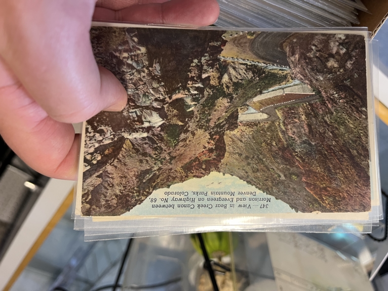 An old postcard, with a photo of CO38 highway, near Evergreen, CO.