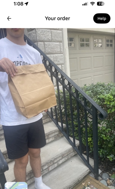 A picture of a headless body holding a bag of food.