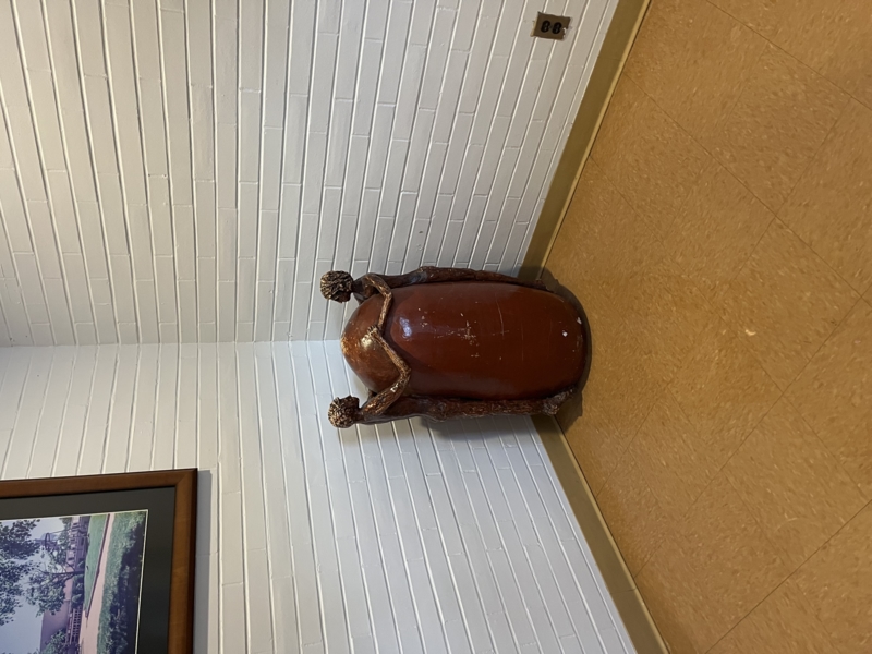 A brown sculpture of two human figures, holding their hands around what looks like a giant egg.