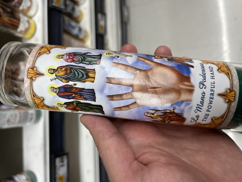 A candle with the religious image The Powerful Hand.