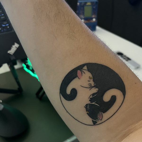 A tattoo of two cats forming a yin-yang symbol.